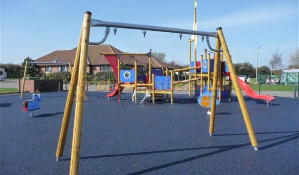 Playground with swings, slides, and climbing equipment on a rubber surface