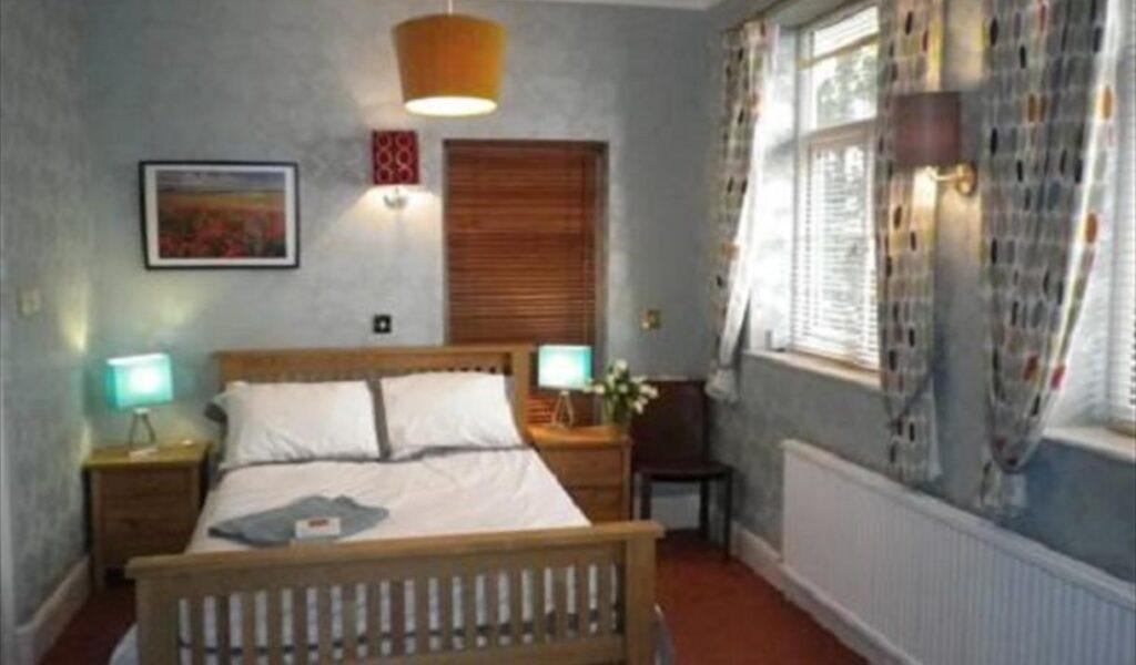 Bedroom with a double bed, bedside lamps, and a window with patterned curtains