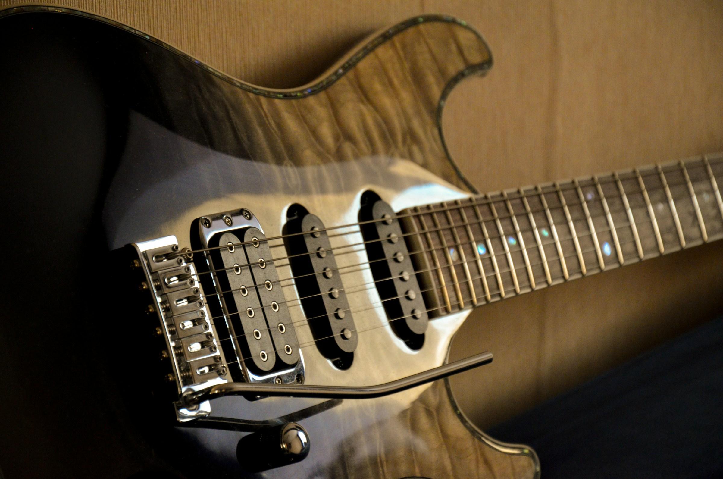 A close up of an electric guitar with a wood finish.