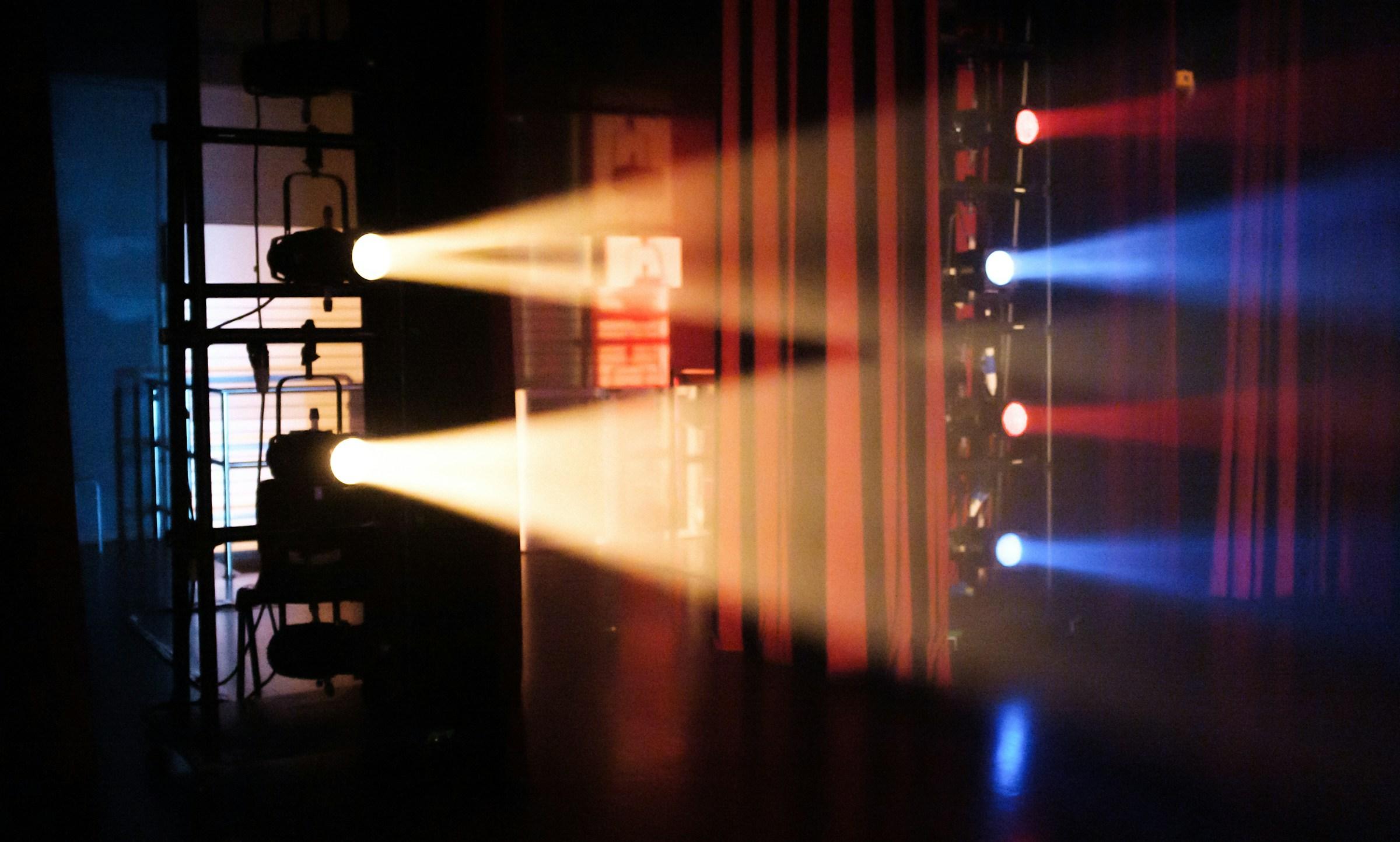 A collection of theatre spotlights shine yellow, blue and red lights.