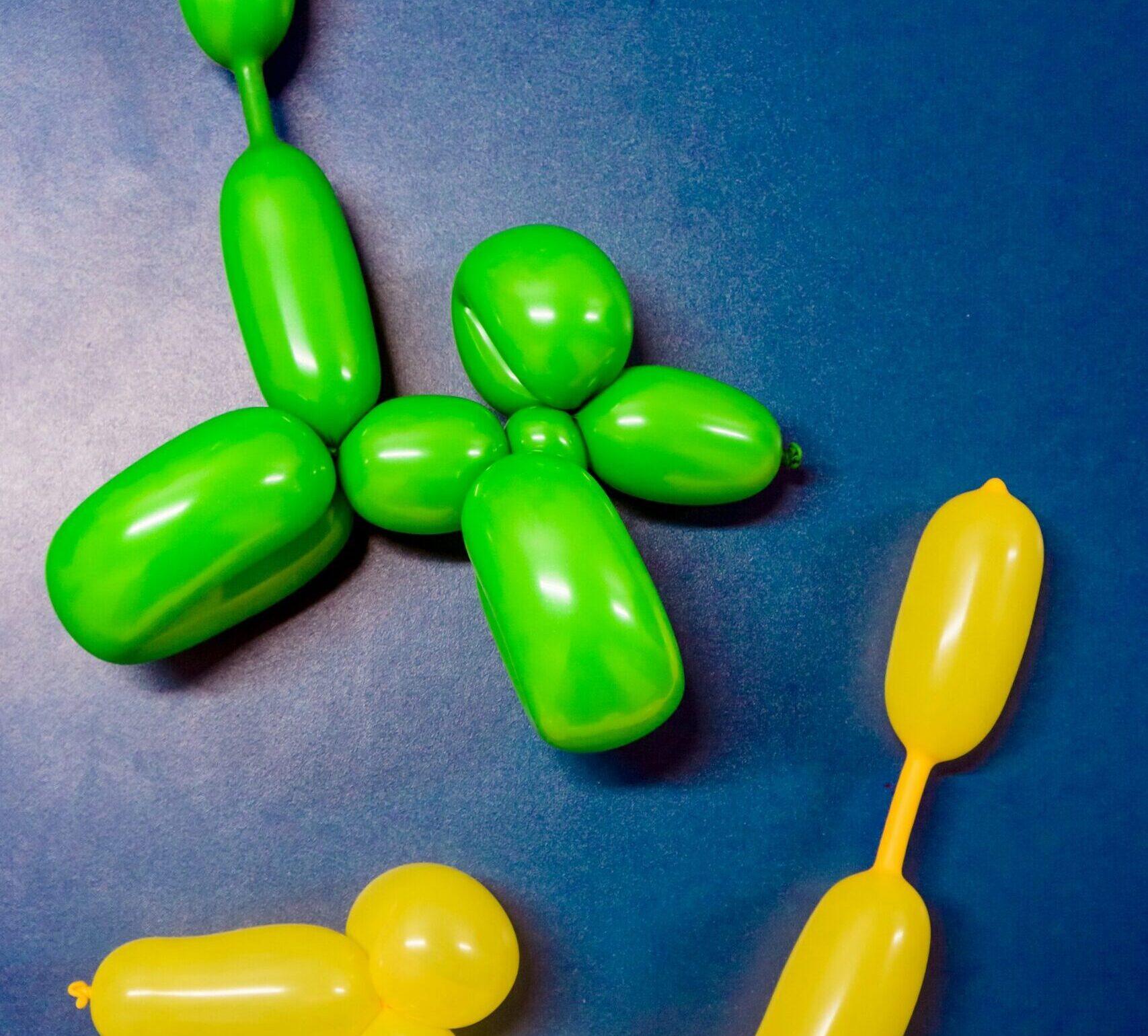 Two balloon dogs with long tails, one green and the other yellow on a blue background.