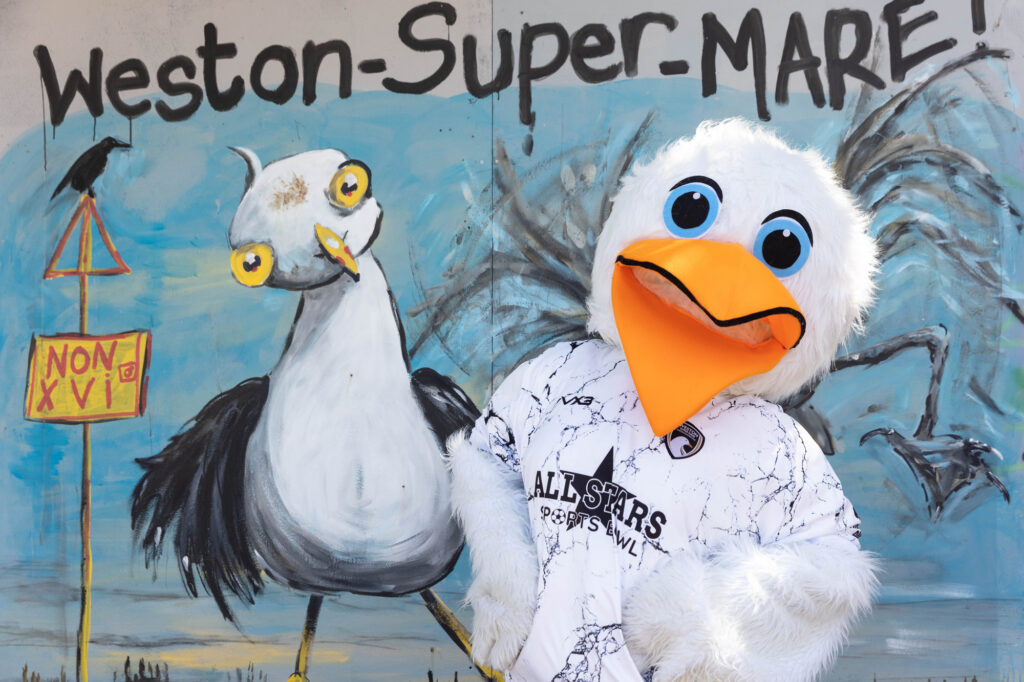 A seagull mascot comes face to face with a seagull on a mural
