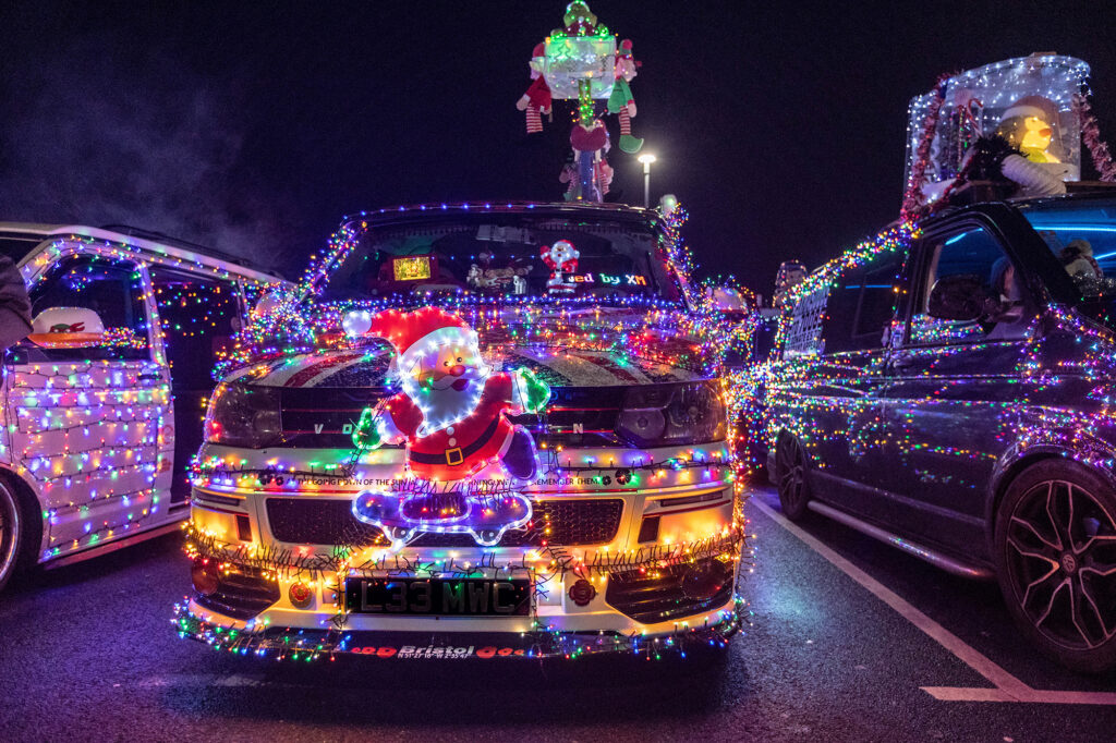 A VW van covered in Christmas lights with a big Santa on the grille during the Weston-super-Mare Vee Dubs Christmas Cruz