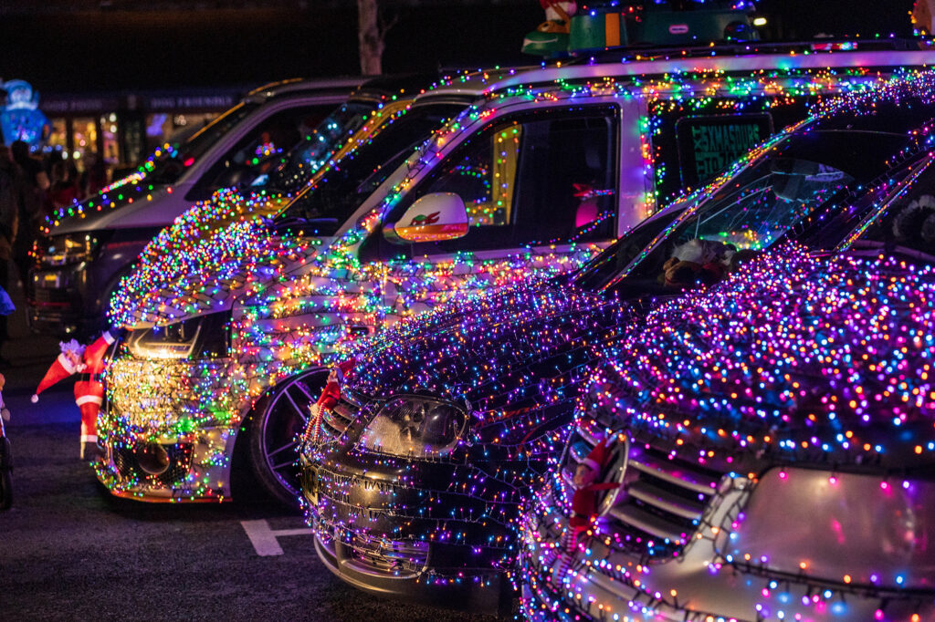 A line up of VW vans decorated with Christmas lights