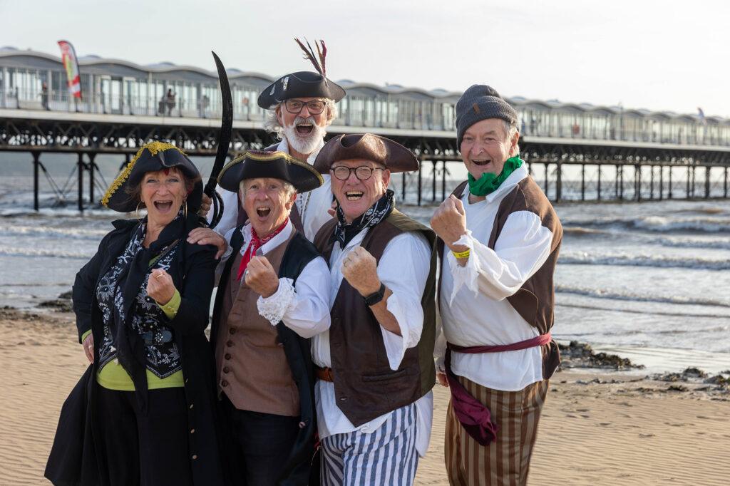 All five members of the Brace Marauders Sea Shanty band in front of the pier at Weston-super-Mare