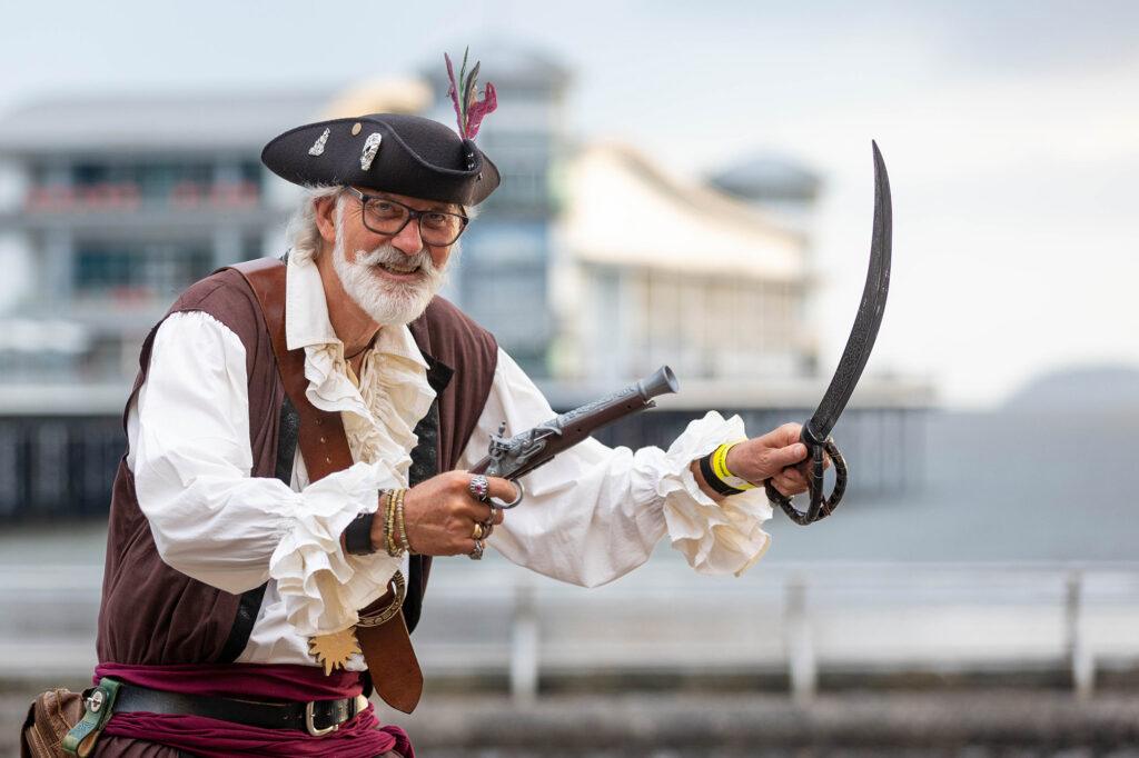 A man dressed as a pirate for the Weston-super-Mare Sea Shanty Festival holding a pistol and a sword