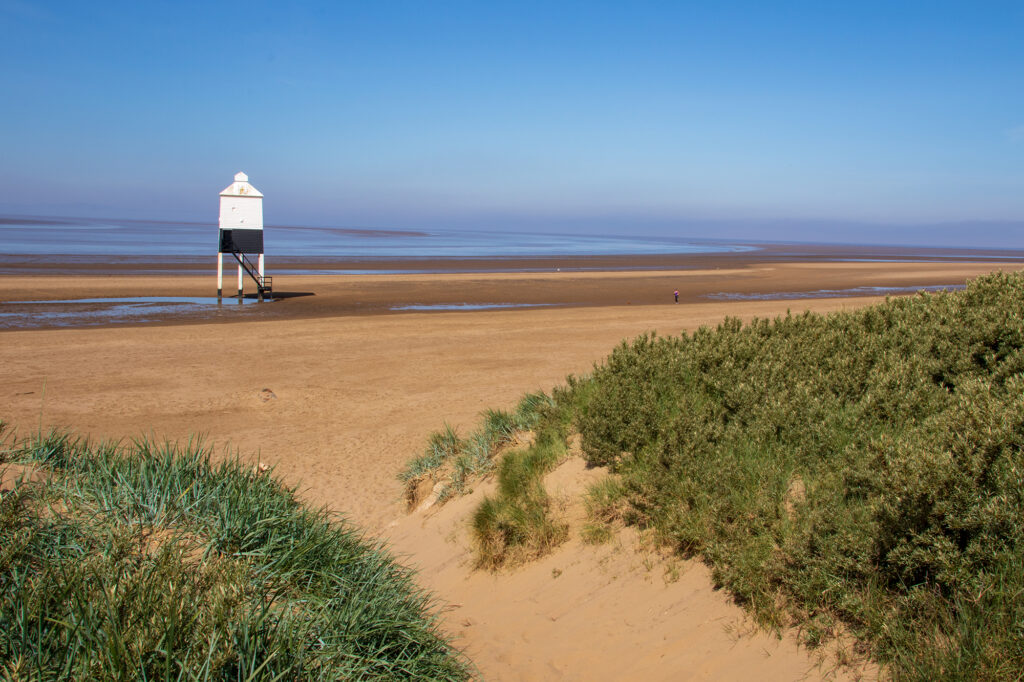 Through the sand dunes looking at Burnham lighthouse which sits on a seven-mile stretch of sandy beach