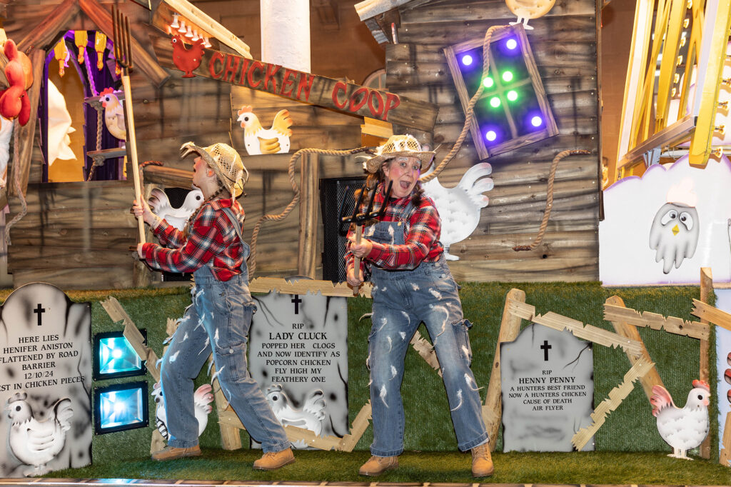 Two performers holding pitchforks in a farmyard scene on a carnival cart at the Weston-super-Mare Carnival