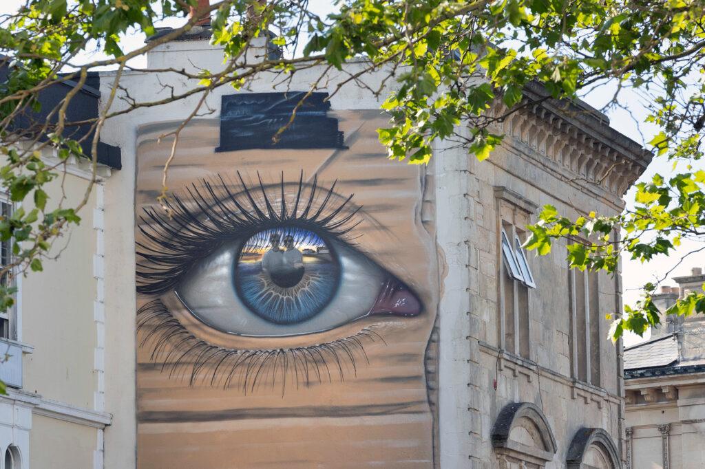A mural of a giant eye with two people painted in the iris on a wall in Weston-super-Mare as part of the town's street art festival