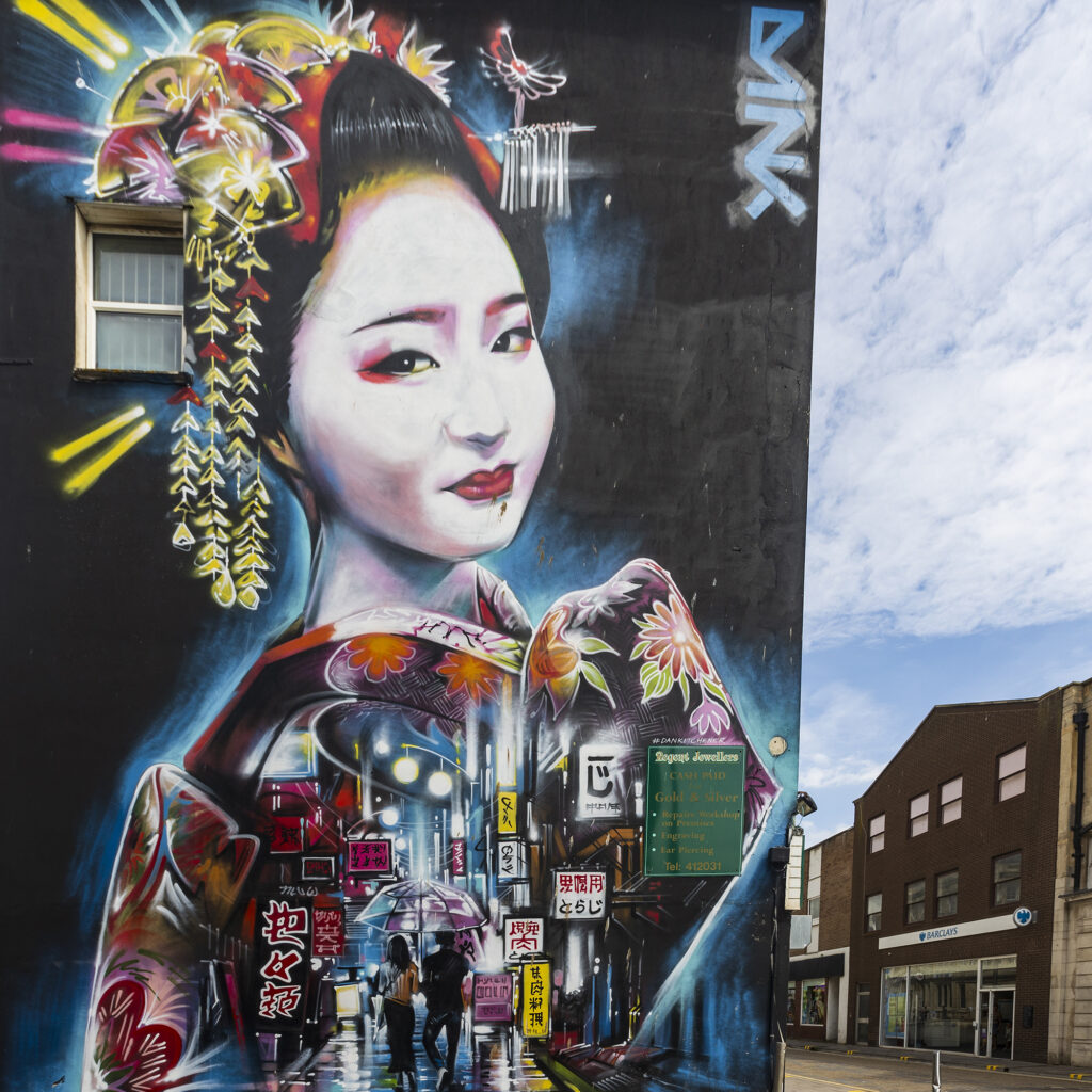 Mural of an Oriental lady whose clothes represent a street scene painted on a wall in Weston-super-Mare
