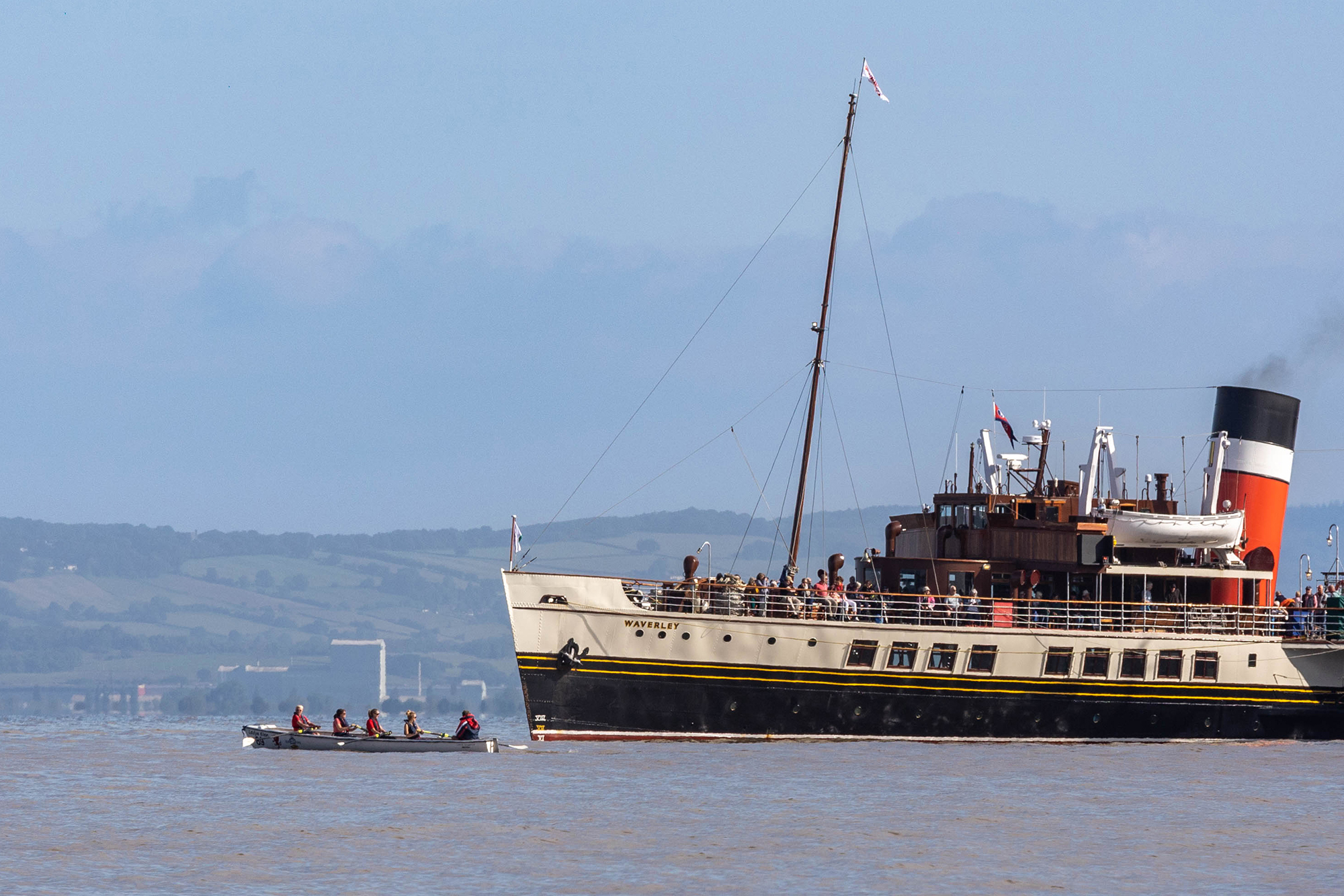 A small rowing boat is dwarfed as it comes alongside the Waverley paddle steamer