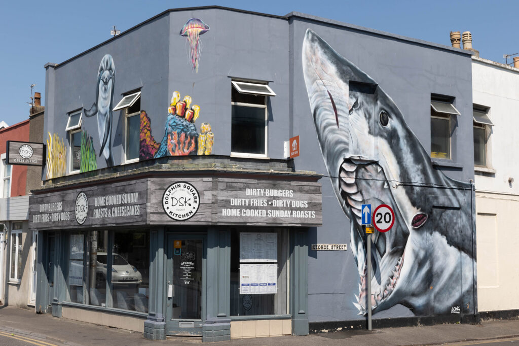 A giant shark with its mouth wide open and baring its teeth painted on the side of a cafe in Weston-super-Mare