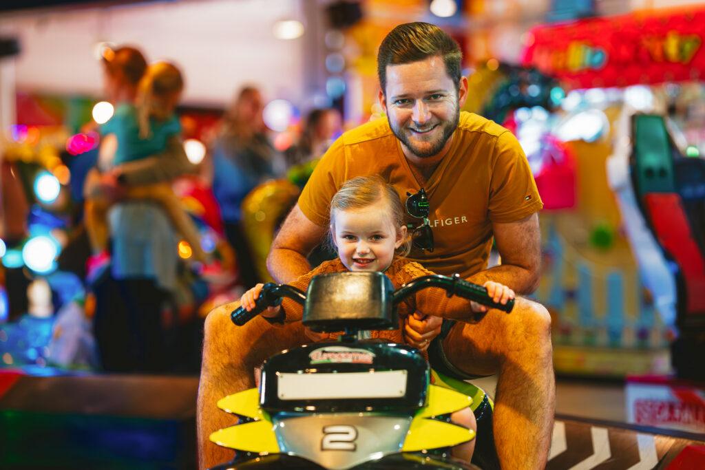 A dad and small child on the disco bikes at the Grand Pier, Weston-super-Mare