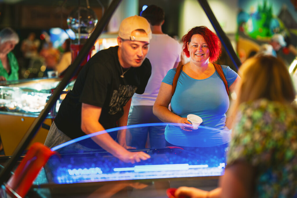 A man tries his luck on the slots on the Grand Pier, Weston-super-Mare while a lady holds the money cup