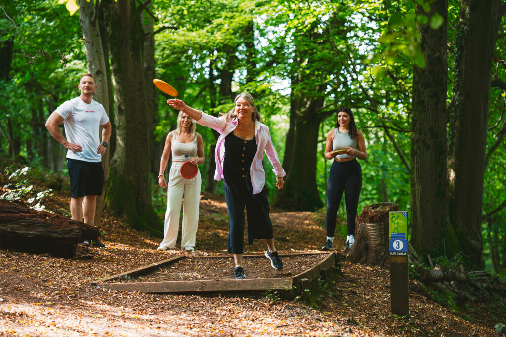 A lady throws a frisbee at the Mendip Activity Centre's frisbee golf activity