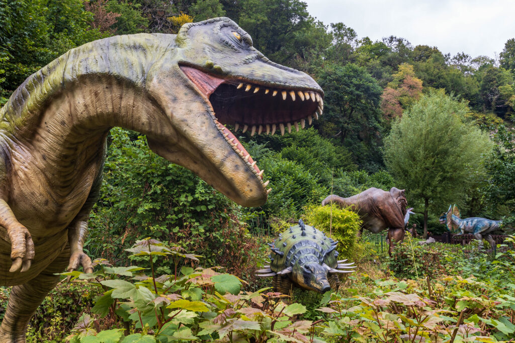 A dinosaur rears up in the foreground and roars at three other prehistoric creatures at Dinosaur Valley at Wookey Hole