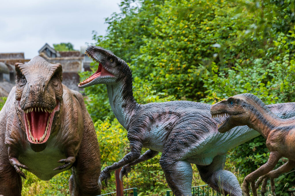 Three dinosaurs, all showing their teeth at Dinosaur Valley at Wookey Hole
