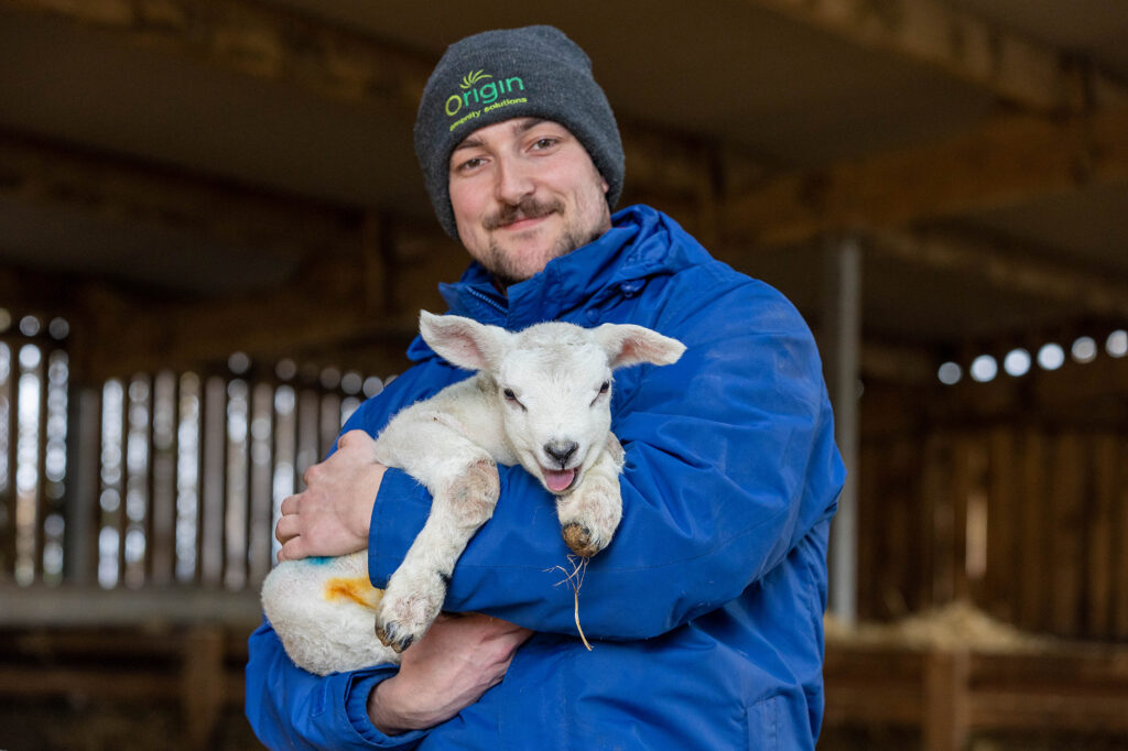 A farmer holding a baby lamb at Court Farm animal attraction near Weston-super-Mare