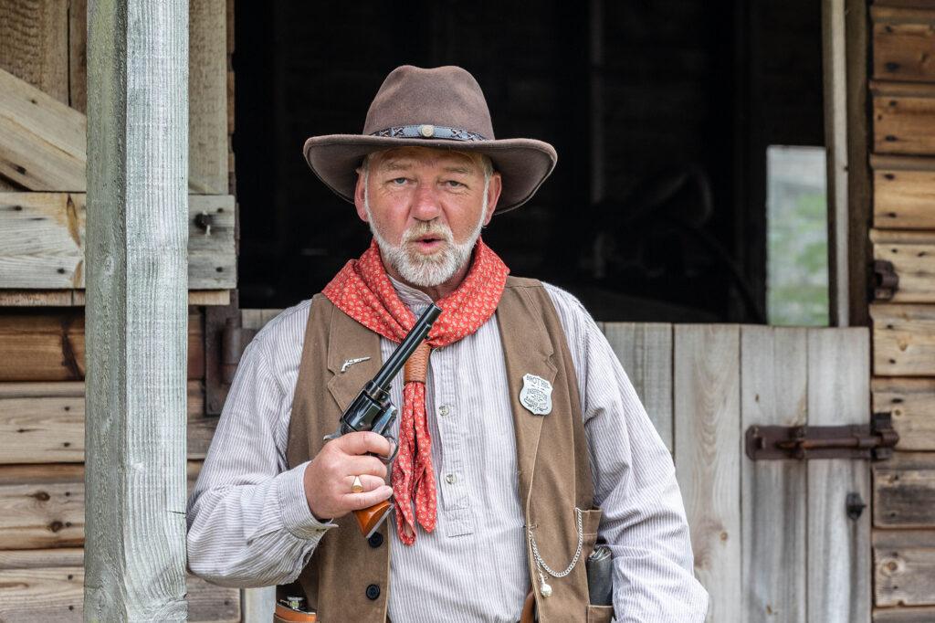 A cowboy at a Country & Western weekend at Court Farm, near Weston-super-Mare ,blows the smoke off his gun
