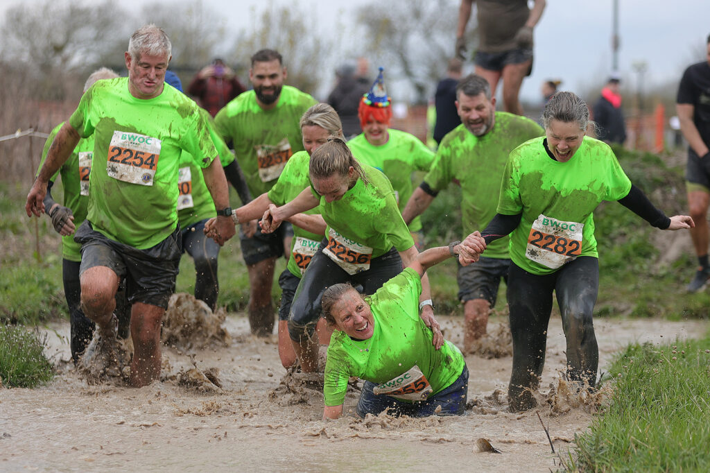 A team in the Puxton Park Mud Master try to lift one of their teammates who has fallen during a water stretch at the Puxton Park Mud Master