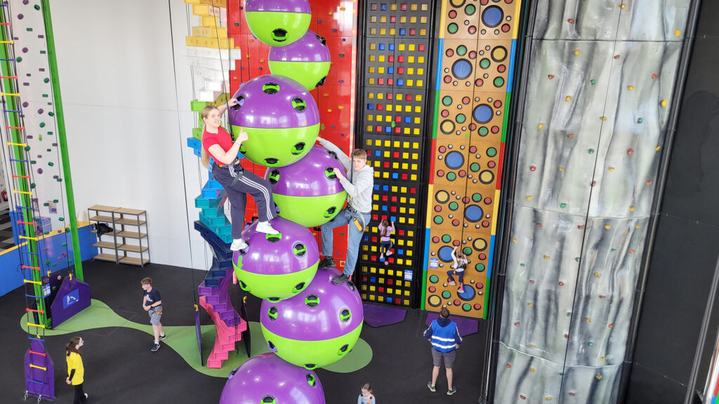 Two people on climbing balls looking down at lots of other users at the Rock Up Indoor Climbing Centre, Weston-super-Mare