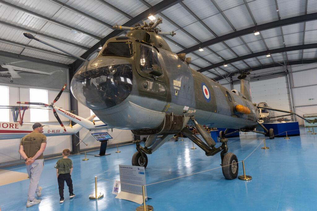 A dad and child are dwarfed by a helicopter in the Weston-super-Mare Helicopter Museum