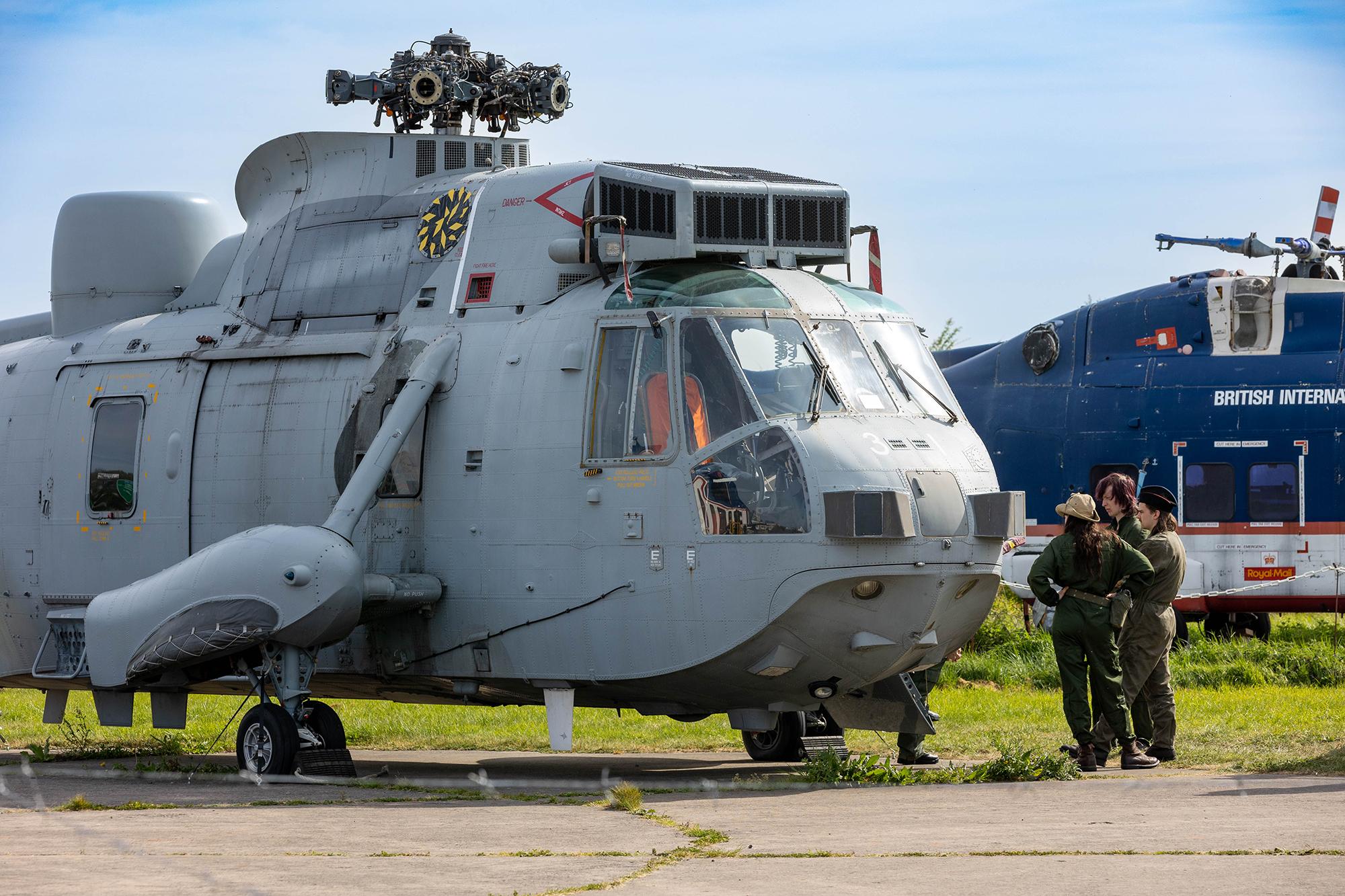 Three maintenance staff standing by a giant military helicopter at the Weston-super-Mare Helicopter Museum