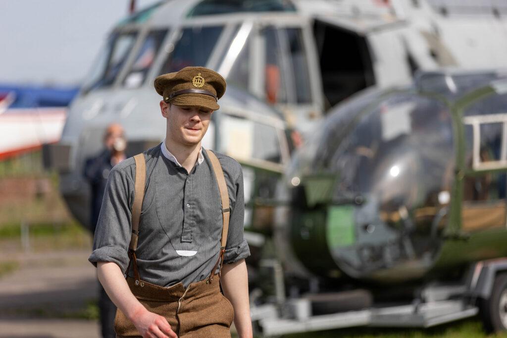 A re-enactor walks past two helicopters during the Military History Weekend at Weston-super-Mare Helicopter Museum