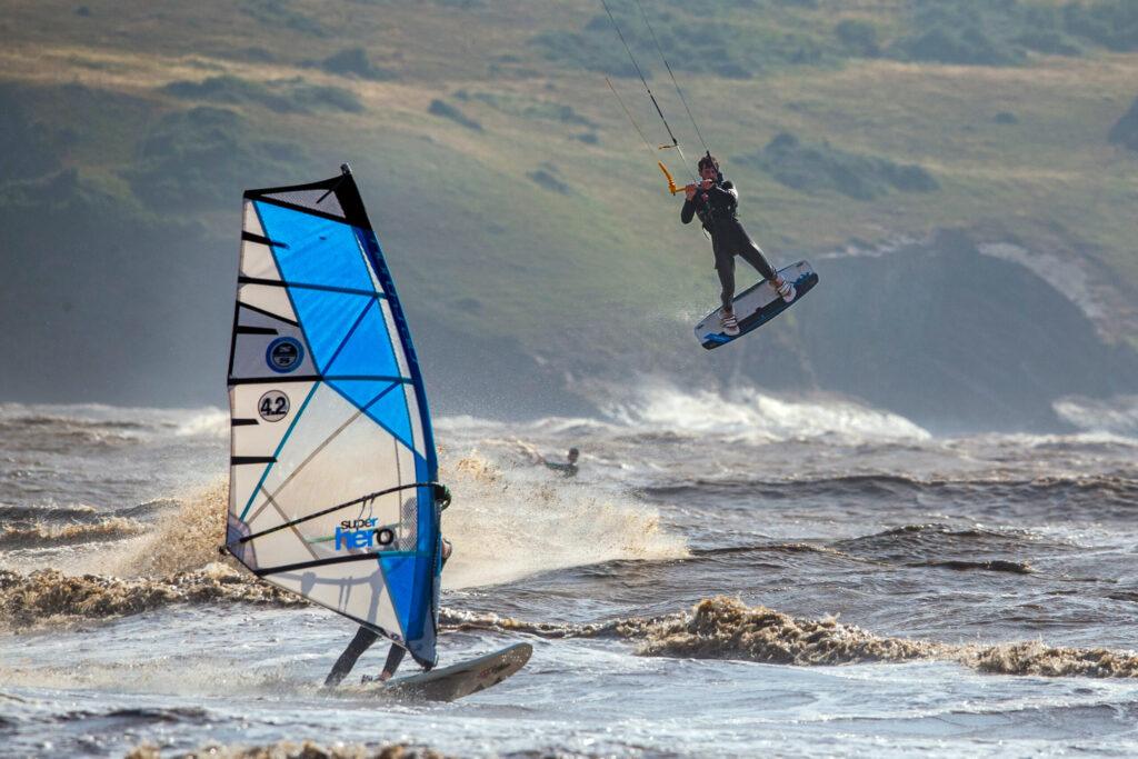 A kite surfer is lifted into the air as a windsurfer cuts past him at Weston-super-Mare