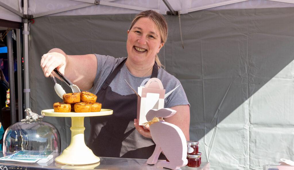 A bakery stall holder picks up a pie with her tongs at the Weston weekly market