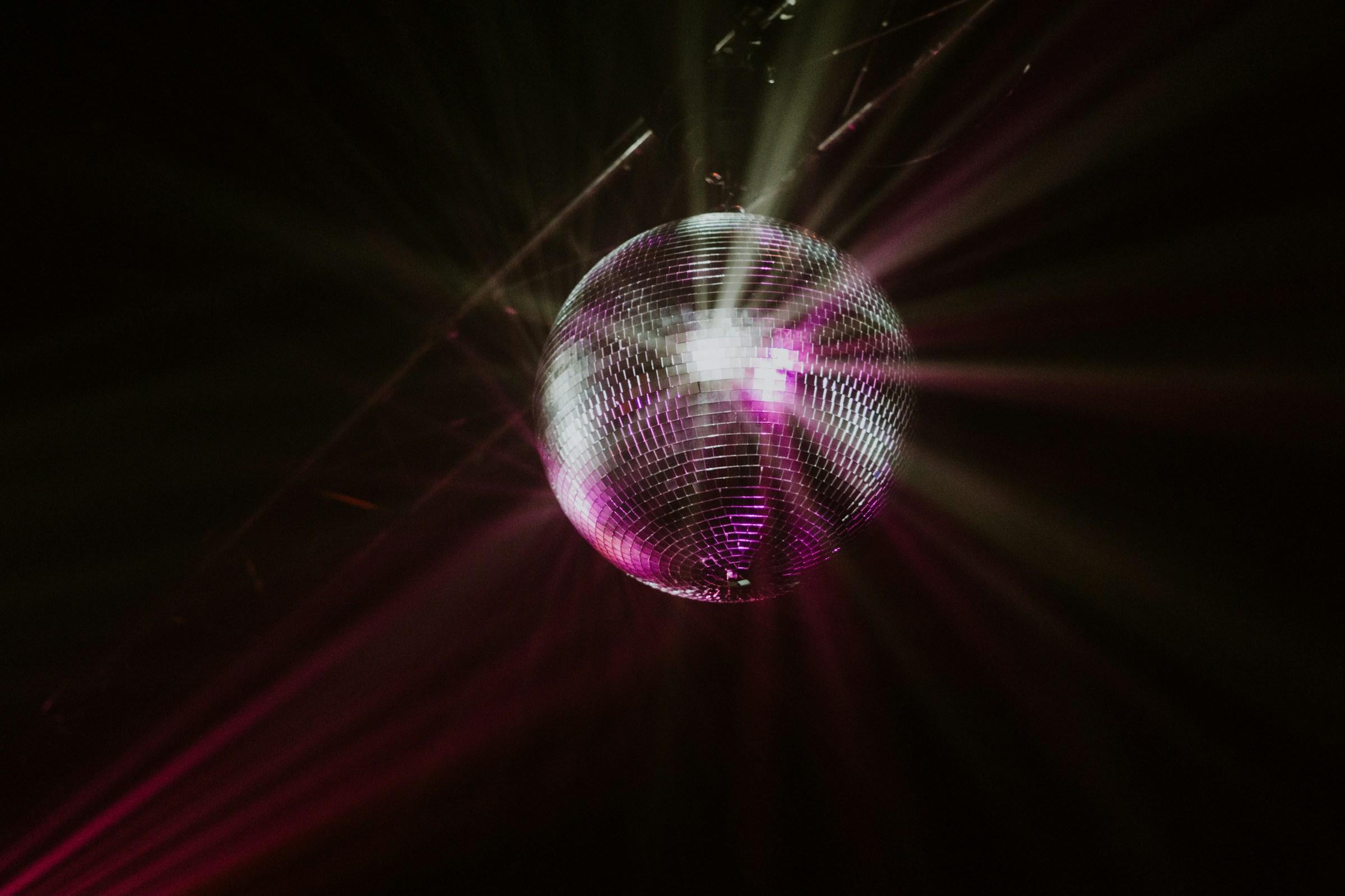 A silver disco ball hangs from a roof in a dark room