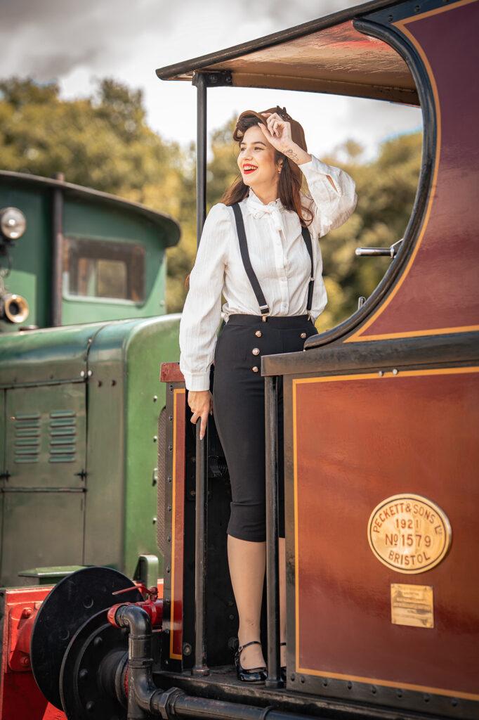 A woman in 1940s dress on the footplate of a vintage train