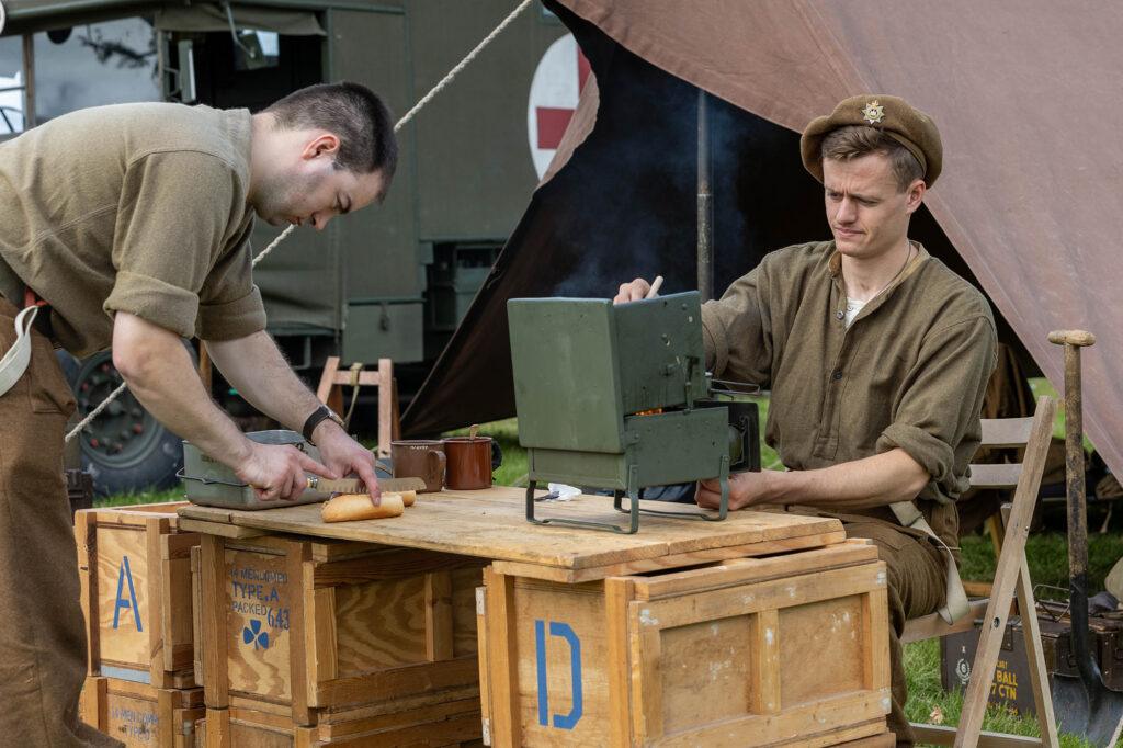 A soldier sits at a small cooker while his colleague cuts bread at the Dig for Victory Show in North Somerset