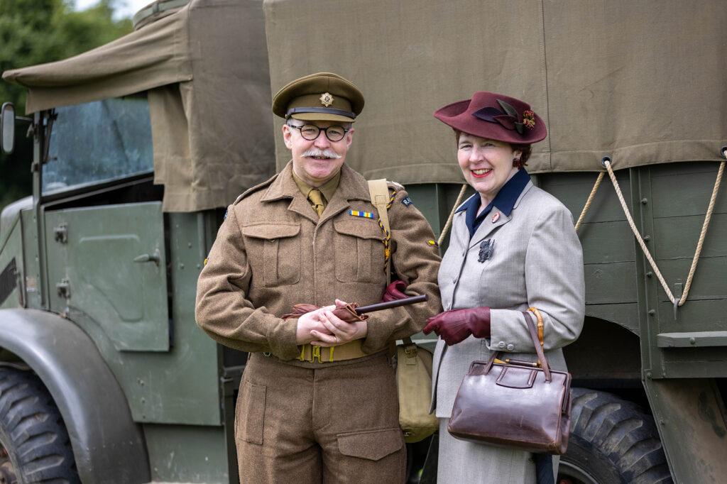 A man in 1940s service uniform with a lady from the same area inn front of a military truck at the Dig for Victory Show in North Somerset