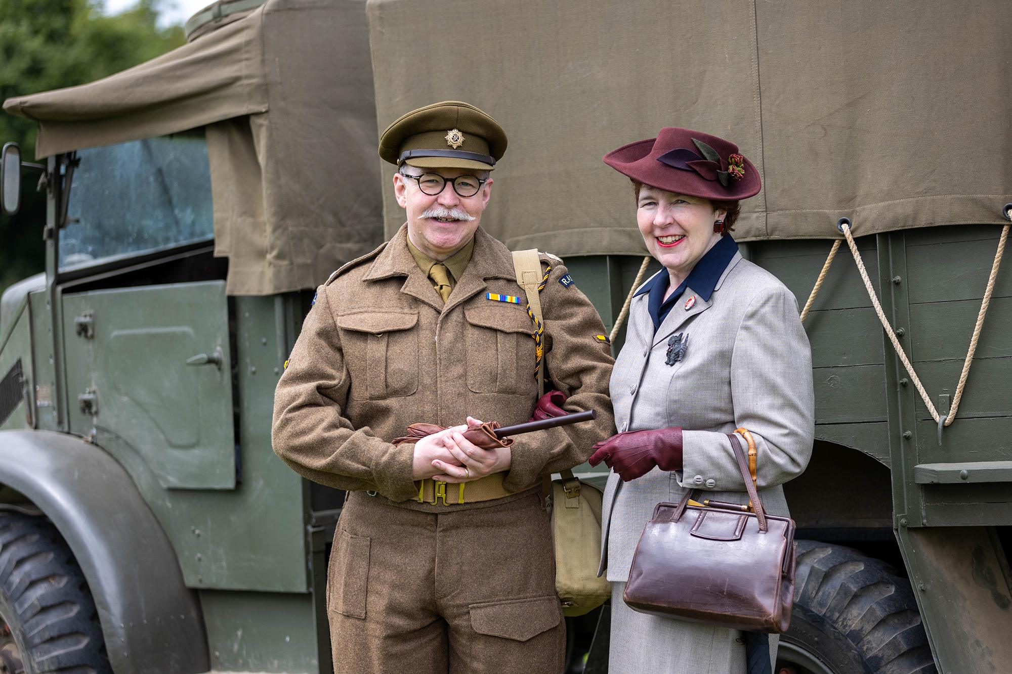 A man in 1940s service uniform with a lady from the same area inn front of a military truck at the Dig for Victory Show in North Somerset