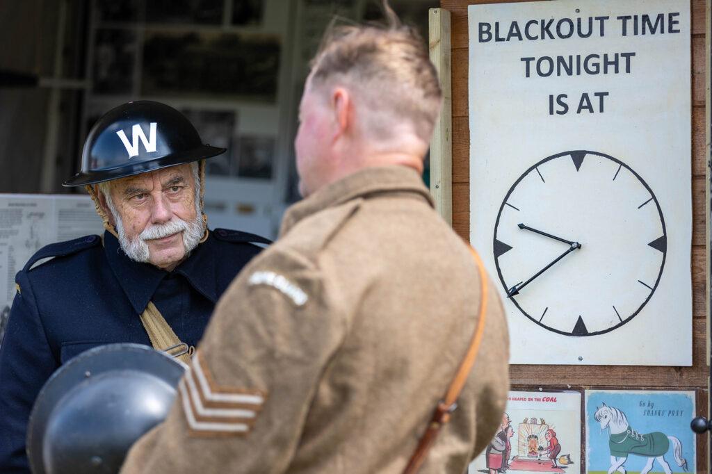 A Home guard warden chats to a soldier next to a sign saying Blackout time is 9.40pm at the Dig for Victory Show in North Somerset