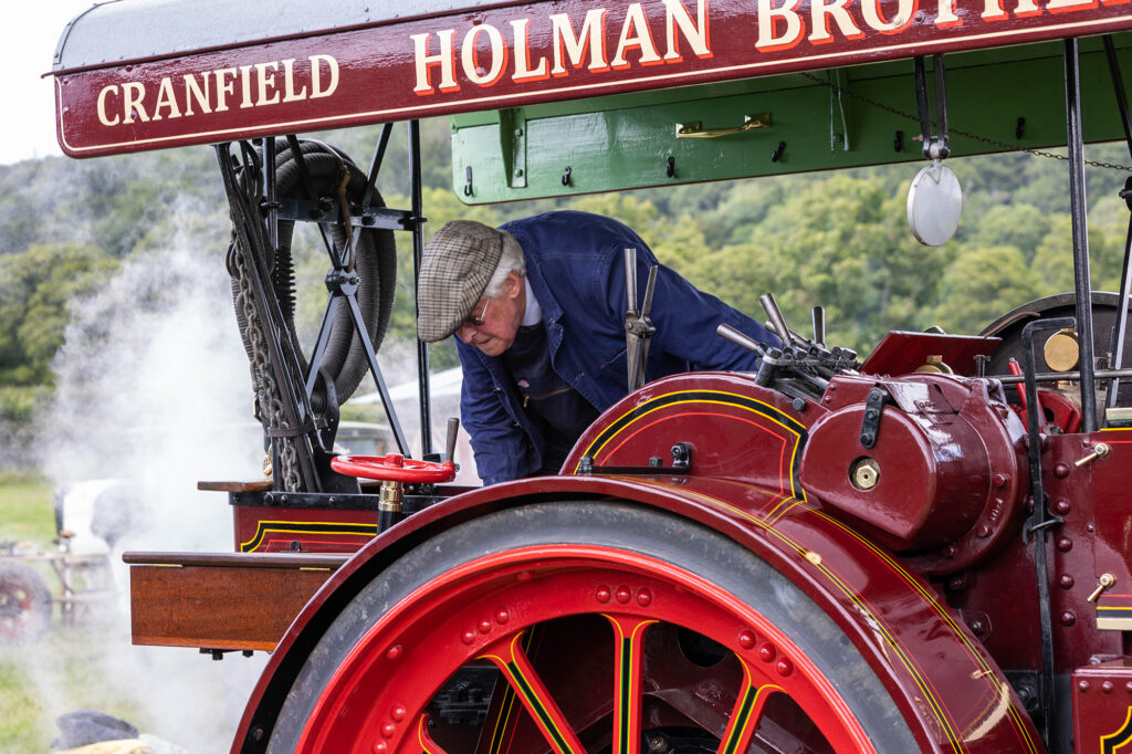 A man mending a red traction engine at the Dig for Victory Show in North Somerset