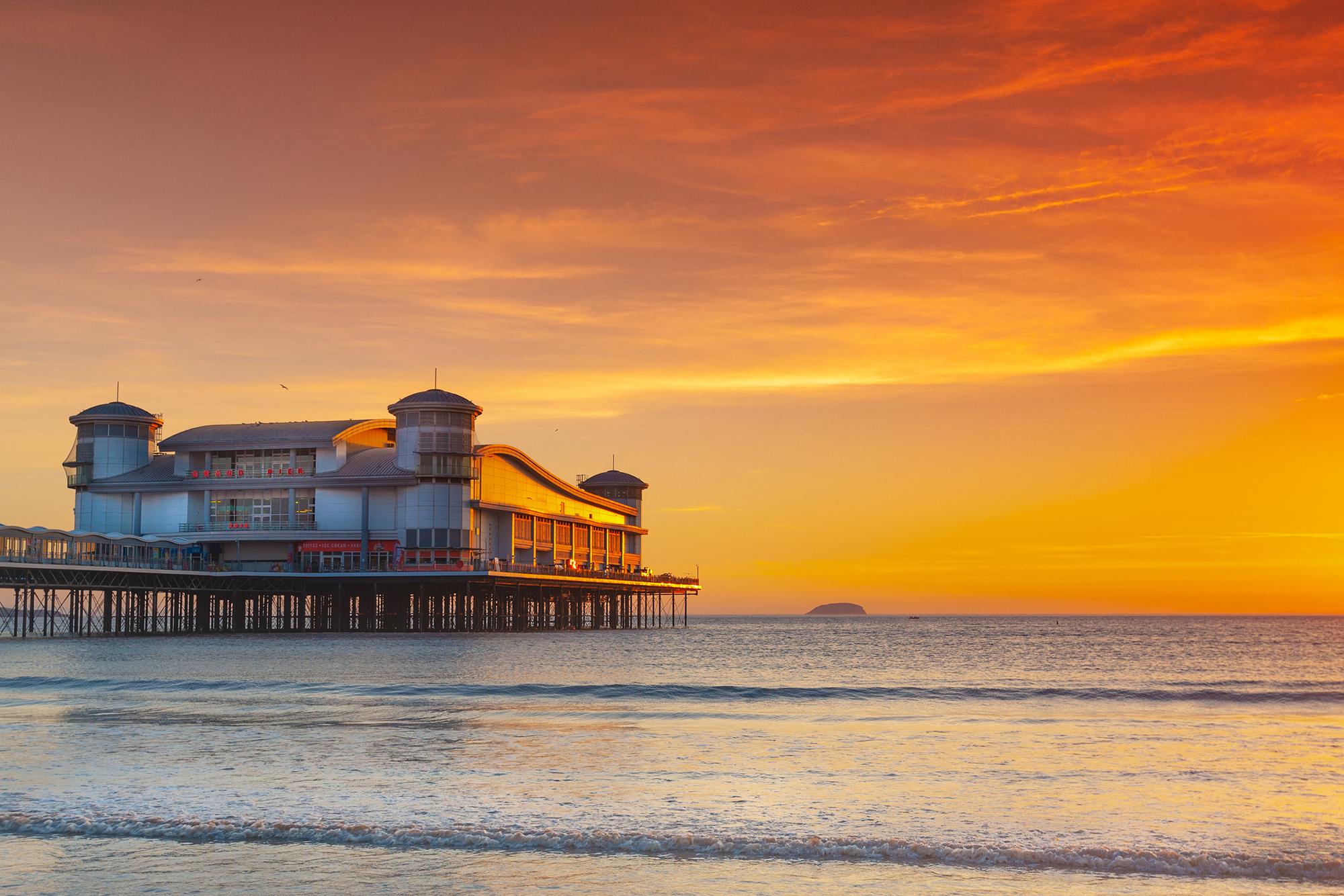 Weston's Grand Pier with a golden sunset and the island of Flat Holm in the background