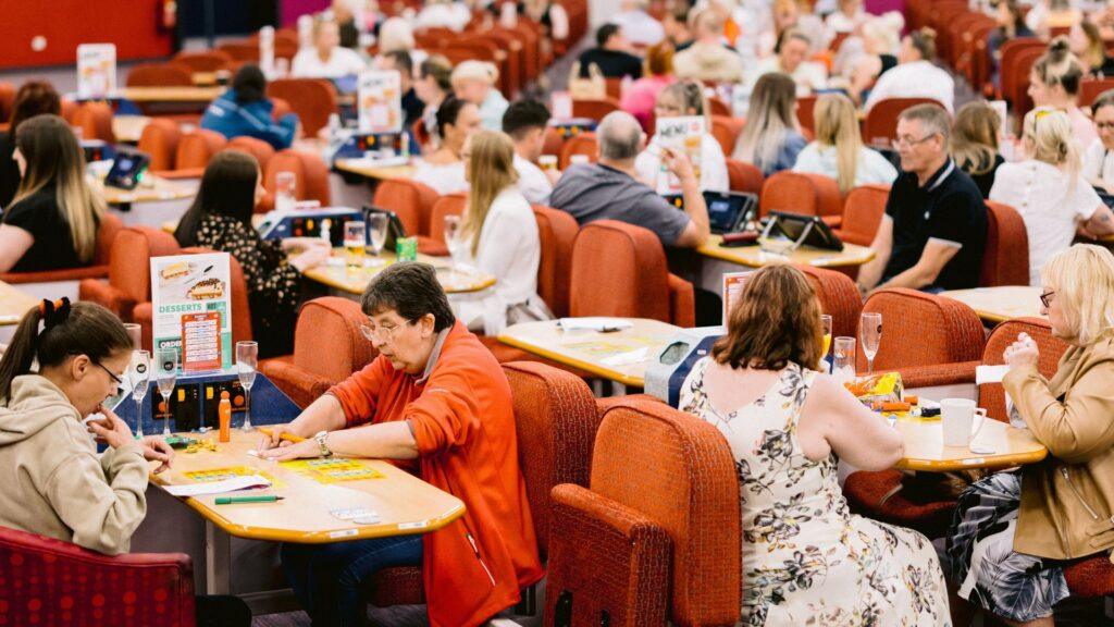 A crowded bingo hall with lots of players sitting at tables