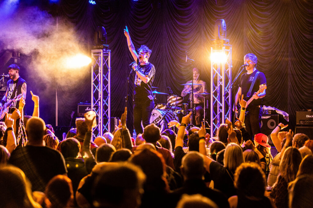 The lead singer of a band takes the applause from the large crowd in front of him