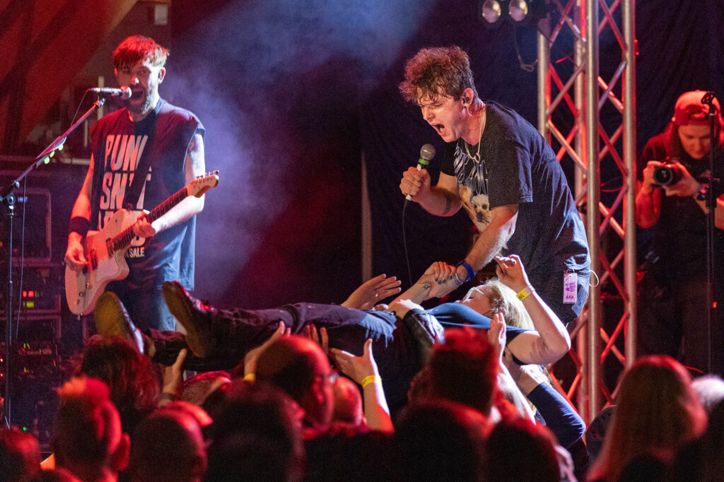 A lady crowd surf close to the stage as the band perform