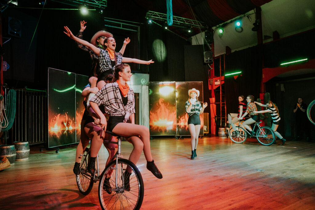 Four people riding one bicycle in a circus performance at Wookey Hole