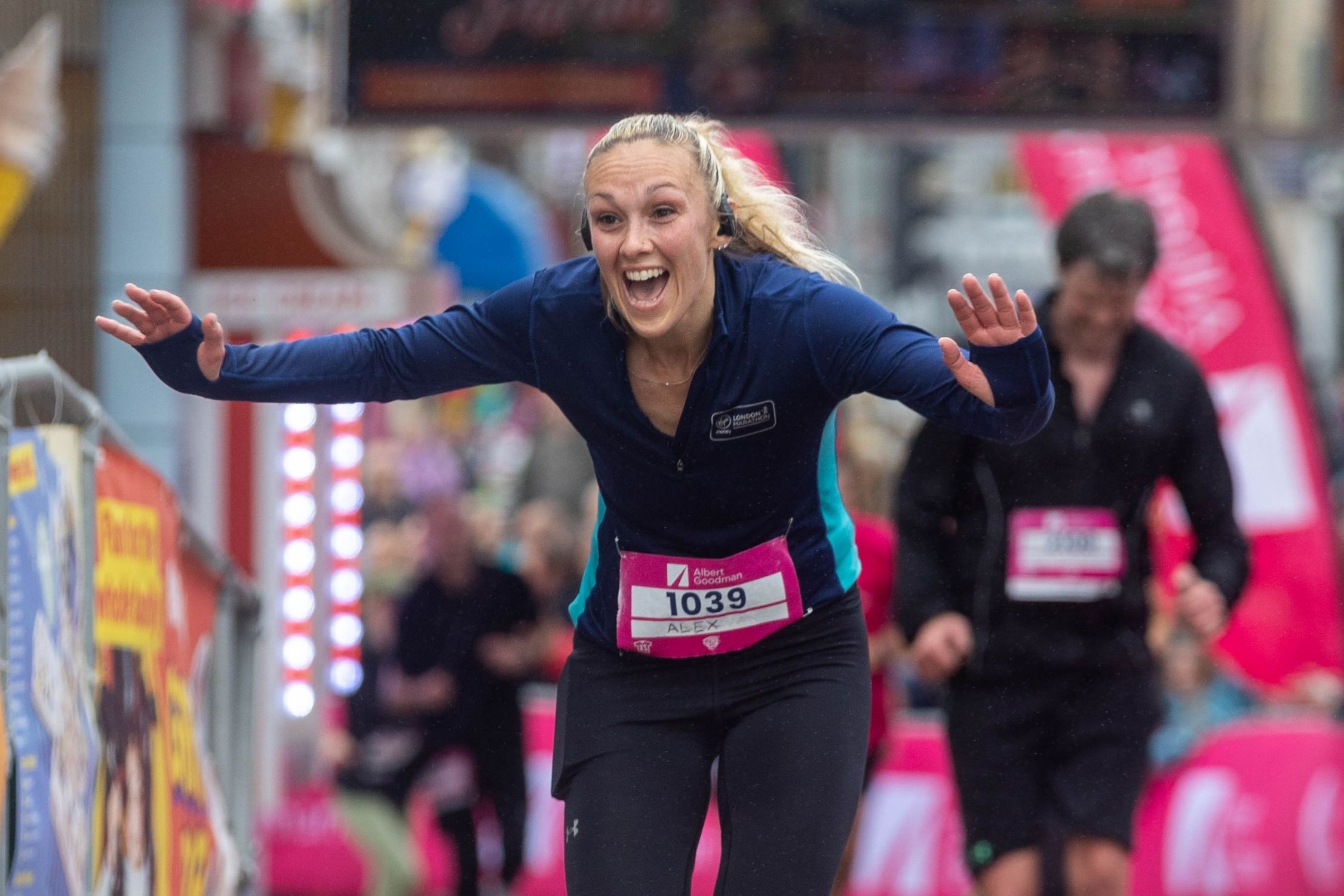 A female runner displays a huge smile and has her arms outstretched after recognising someone in the crowd at the Weston-super-Mare Half Marathon