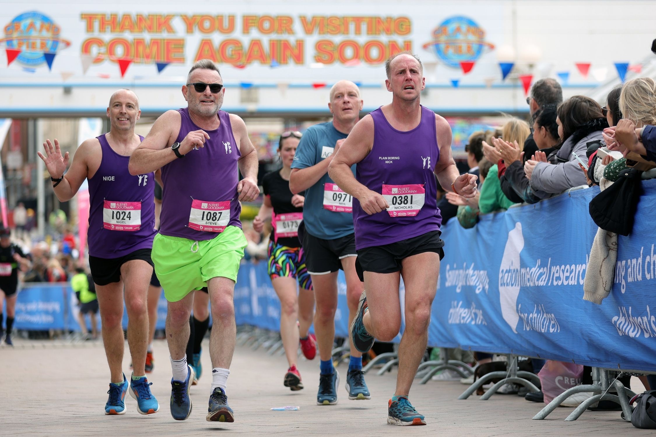 Five runners being applauded by the crowd as they approach the finish of the Weston-super-Mare Half Marathon