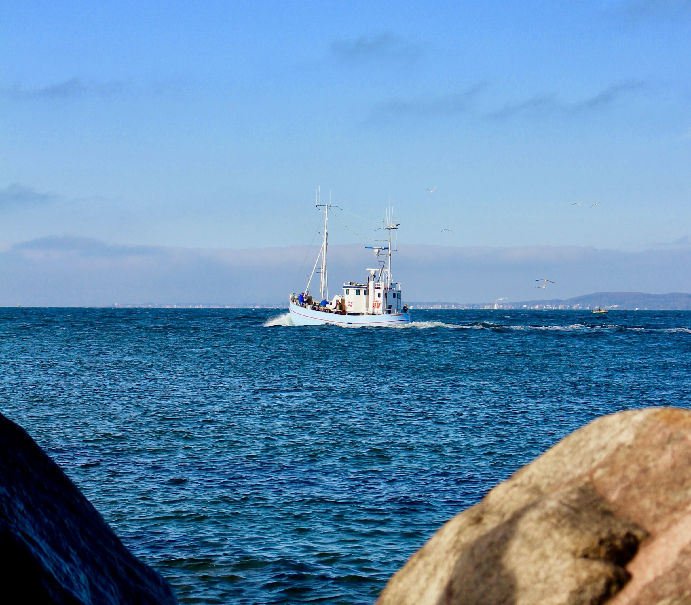 A fishing boat on the sea off in the horizon