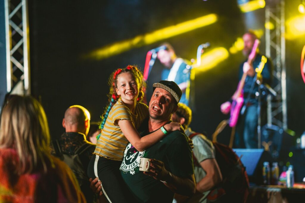 A dad lifts up a teenage girl at a concert