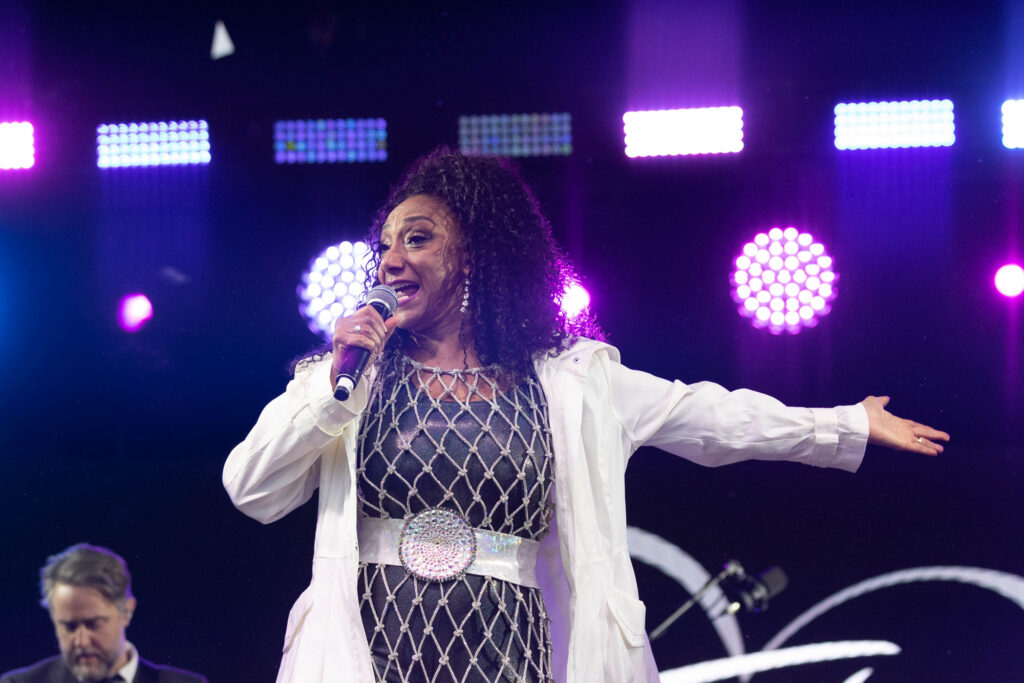 A female singer in full voice with her left arm outstretched