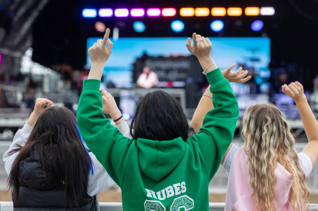 View through the arms of three girls watching a concert