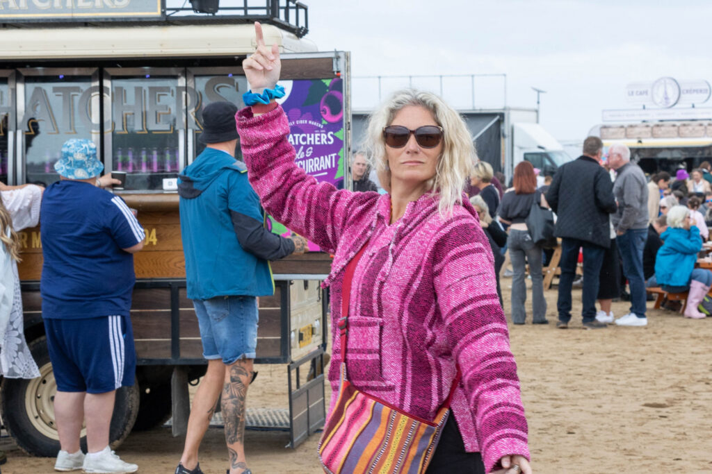 A blonde lady in pink dances at a festival