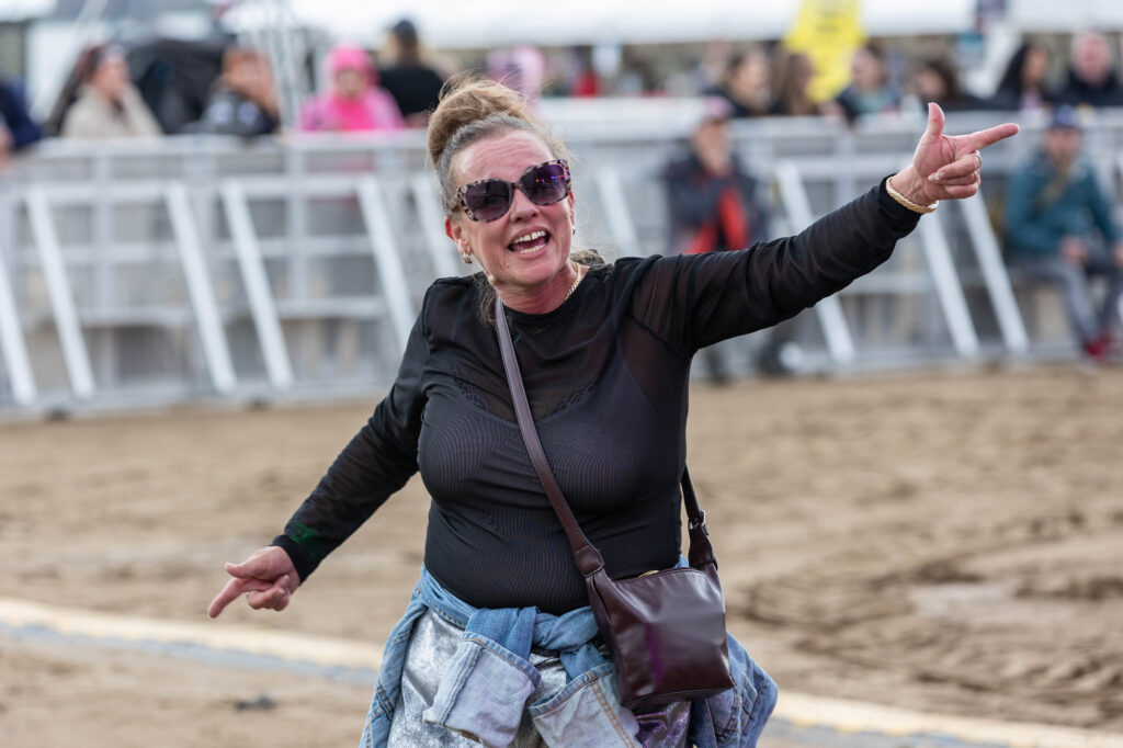 A lone female dancer in black top and sunglasses on the sand at a music festival